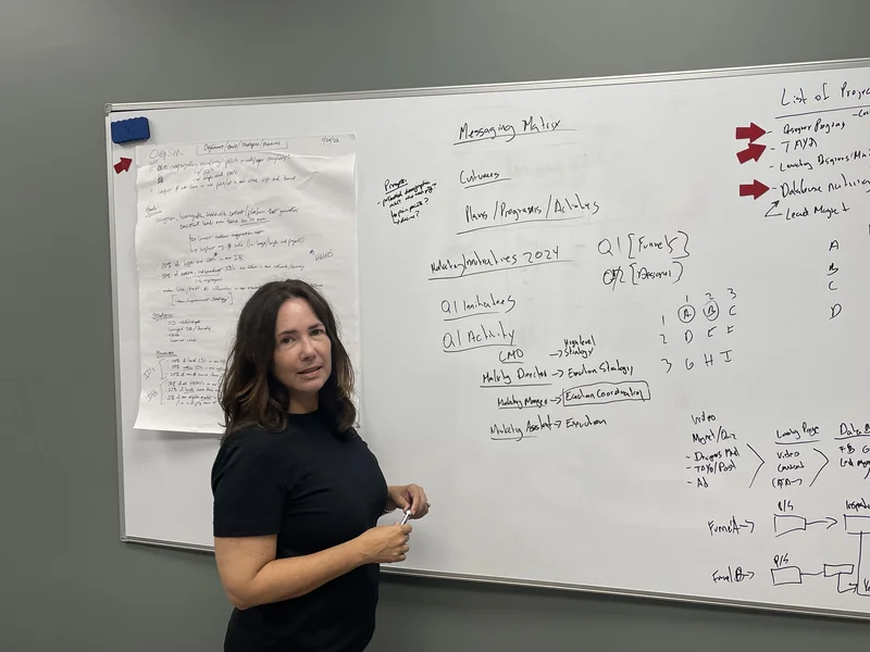 Lisa M. of Paper Moon Painting standing in front of a strategy whiteboard